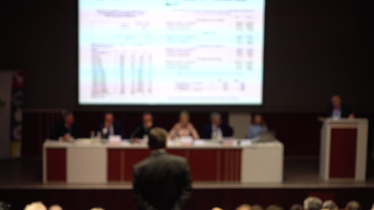Vista borrosa de una conferencia empresarial con oradores y audiencia