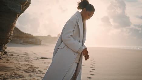 Mujer-Serena-Descansando-En-La-Playa-Jugando-Con-Arena-Bajo-La-Luz-Del-Sol.-Turista-De-Pelo-Negro-Disfruta