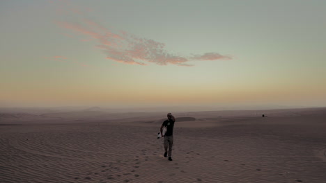 Cooler-Mann-Mit-Sandboard-Geht-Mit-Sonnenuntergang-Auf-Dem-Rücken-In-Der-Wüste-Von-Huacachina-Ica,-Peru