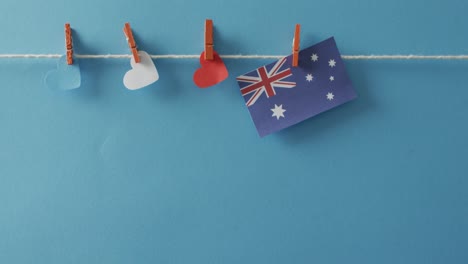 Australische-Flagge-Mit-Sternen-Und-Streifen-Und-Herzformen,-Die-Auf-Blauem-Hintergrund-An-Einer-Linie-Hängen