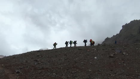 group of people hiking up a ridge in a snow shower, just above plaza argentina on the ascent to aconcagua