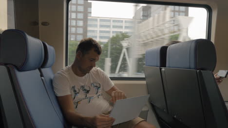 man in train entertaining with laptop