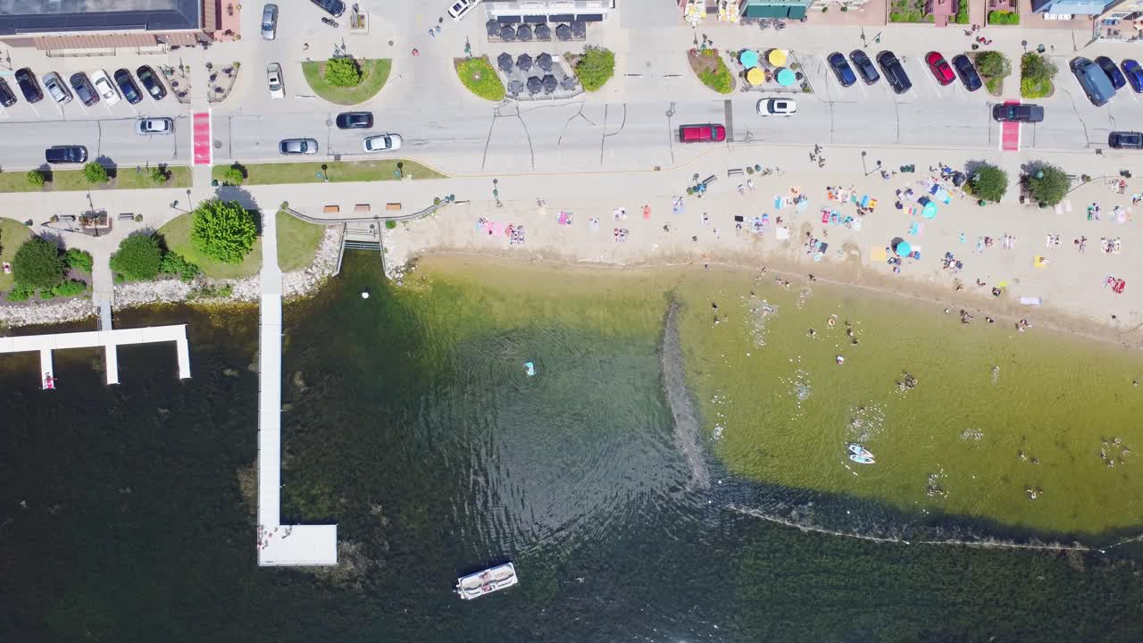 Summer Beach Activities On Pewaukee Lake, Waukesha County, Wisconsin. 4K Slow Motion Aerial PanOver The Fishing Pier And Beach Park.