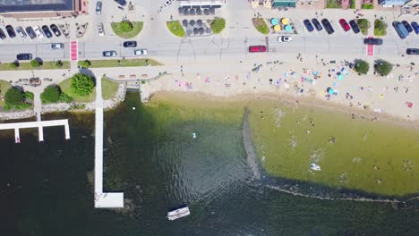 summer beach activities on pewaukee lake, waukesha county, wisconsin. 4k slow motion aerial panover the fishing pier and beach park.