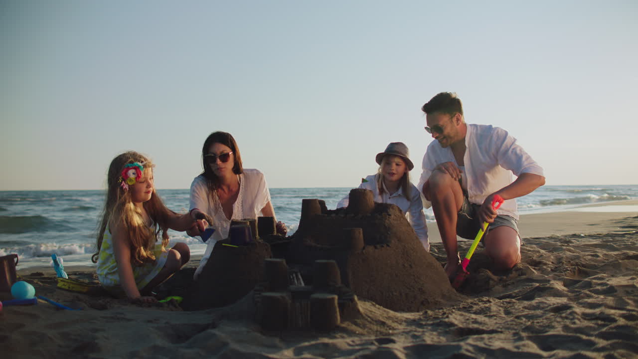 한 가족 이 해변 에 모래 성 을 짓고 있다
