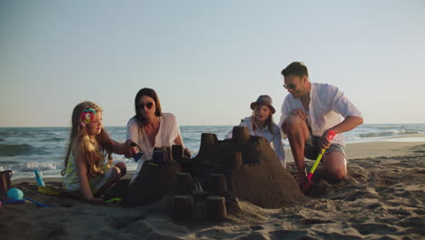 family building a sandcastle on the beach