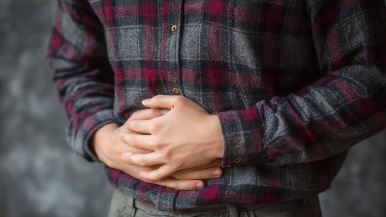 An Individual Experiencing Discomfort: A Close-Up of a Person Holding Their Stomach in a Plaid Shirt, Conveying Feelings of Stomach Pain and Distress