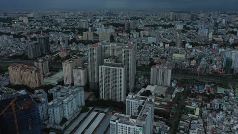 saigon or ho chi minh city, vietnam aerial fly in to urban view of large apartment buildings on very dark stormy evening