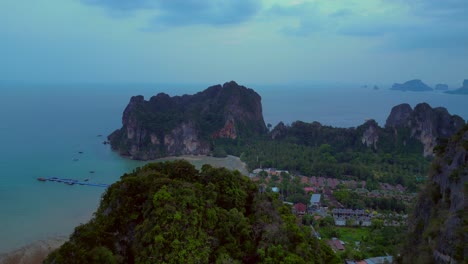limestone cliffs and lush tropical jungle of railay beach, krabi, thailand, at dusk, creating a dramatic and serene landscape. magic aerial view flight fly reverse drone
