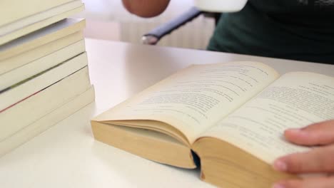 estudiante leyendo un libro y bebiendo café