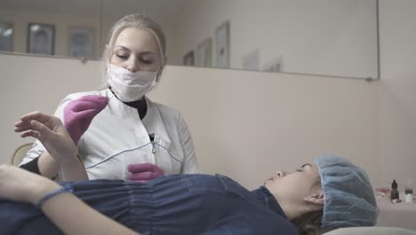 brows master applies paint on client hand before tattooing