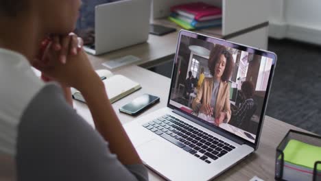 african american woman having a video conference on laptop with female office colleague at office