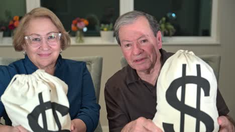 two senior citizens hold up bags of money and put them on the table