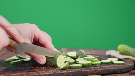 men hands cut cucumber into slices on a wooden cutting board.