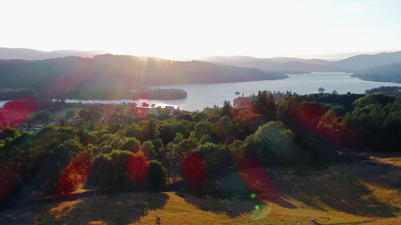 fotografía de un avión no tripulado que muestra ovejas y personas caminando en el campo junto al lago windermere, lake district, reino unido