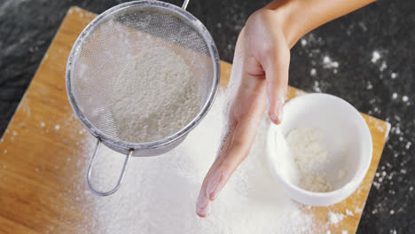 woman sieving flour from the bowl on the wooden board 4k