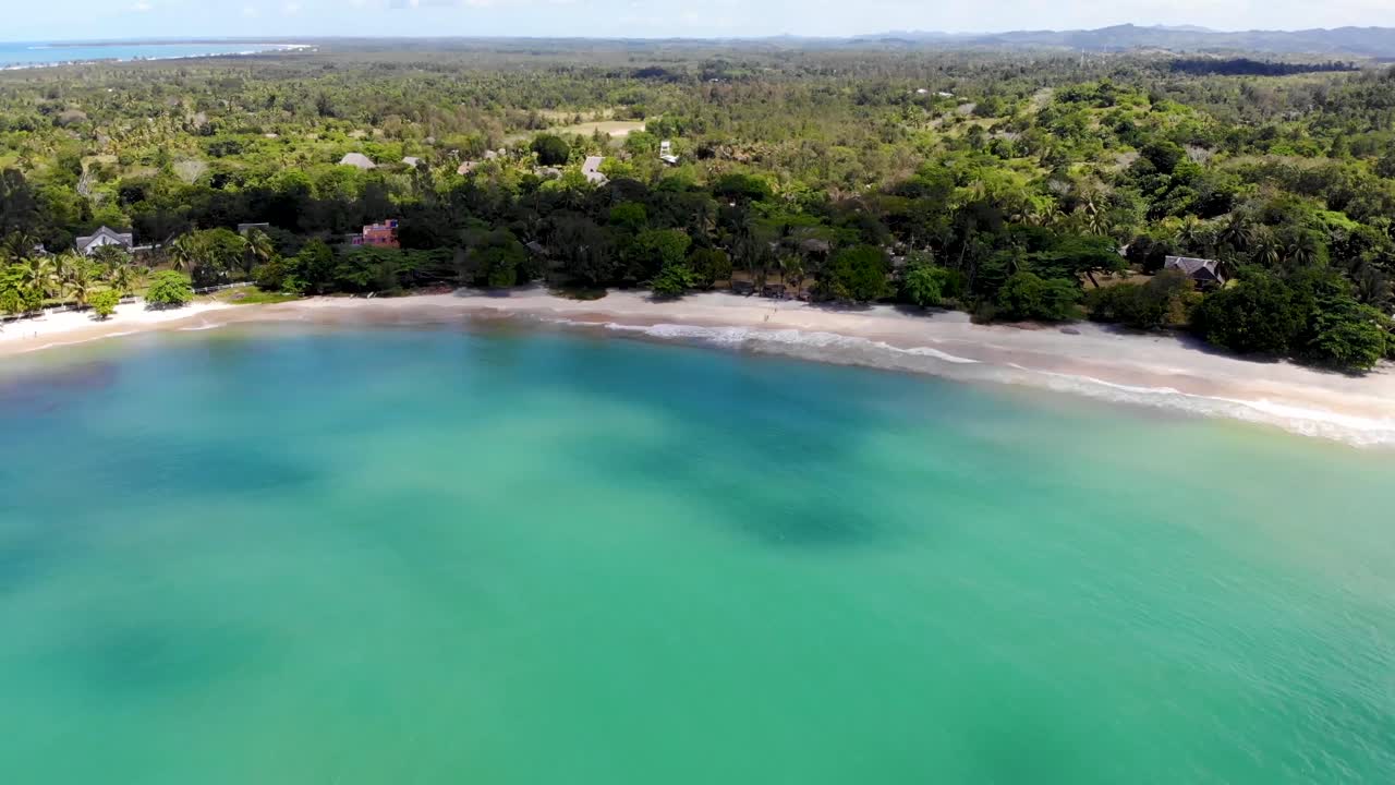playa de arena blanca en madagascar con un mar azul brillante y una costa verde y exuberante en verano