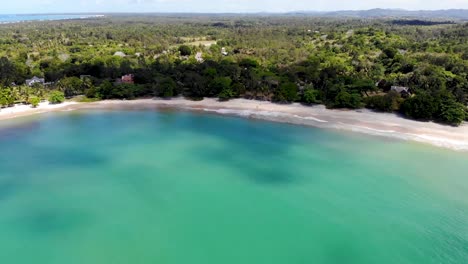 White-Sandy-Beach-In-Madagascar-With-Bright-Blue-Sea-And-Lush-Green-Coastline-In-Summer