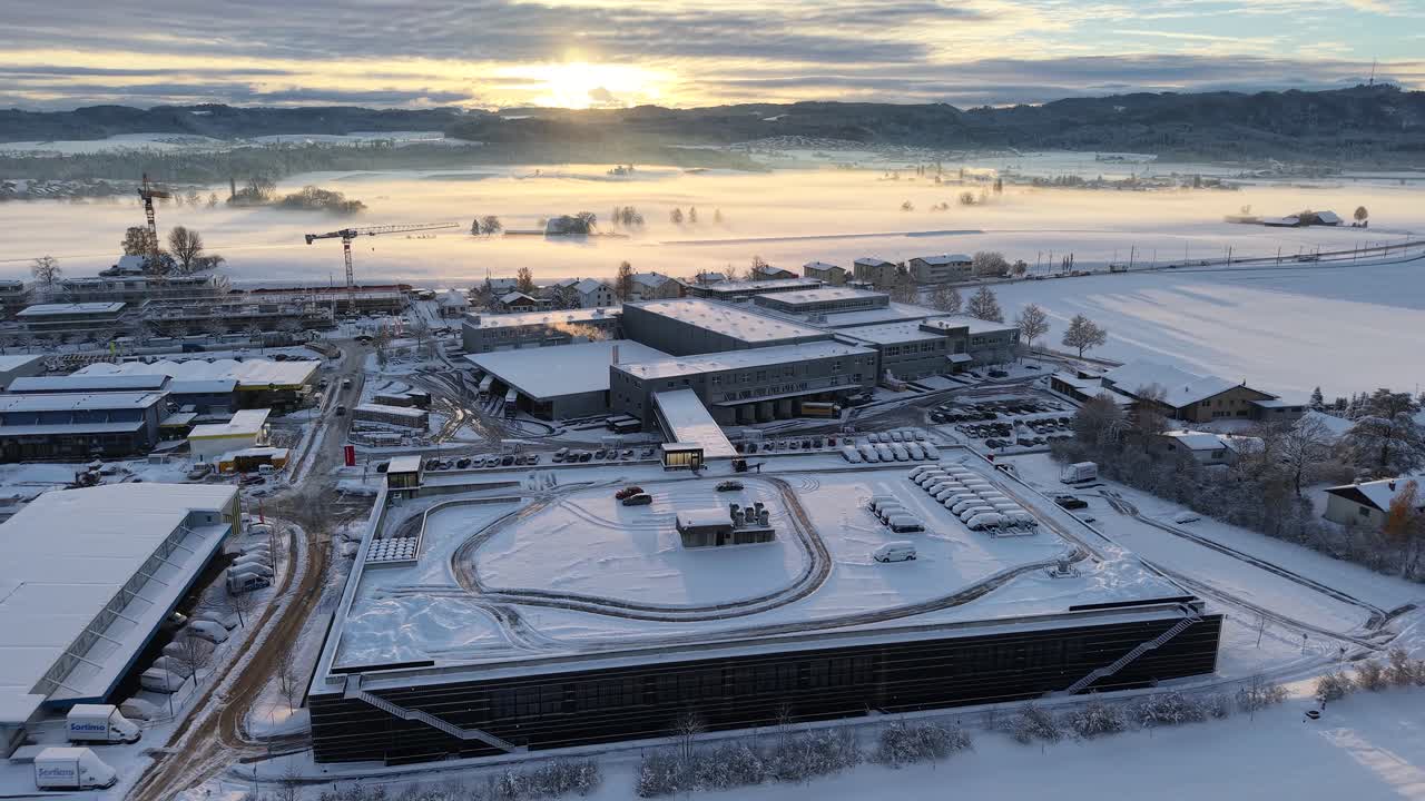Drone footage of a breathtaking sunrise in Switzerland in November 2024. Village in the foreground and landscape in the background. Everything covered in deep snow.