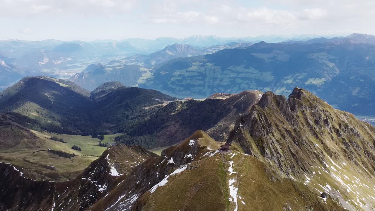 antena cinematográfica de la cima de la montaña de los alpes con una vieja capilla de madera en un pico empinado