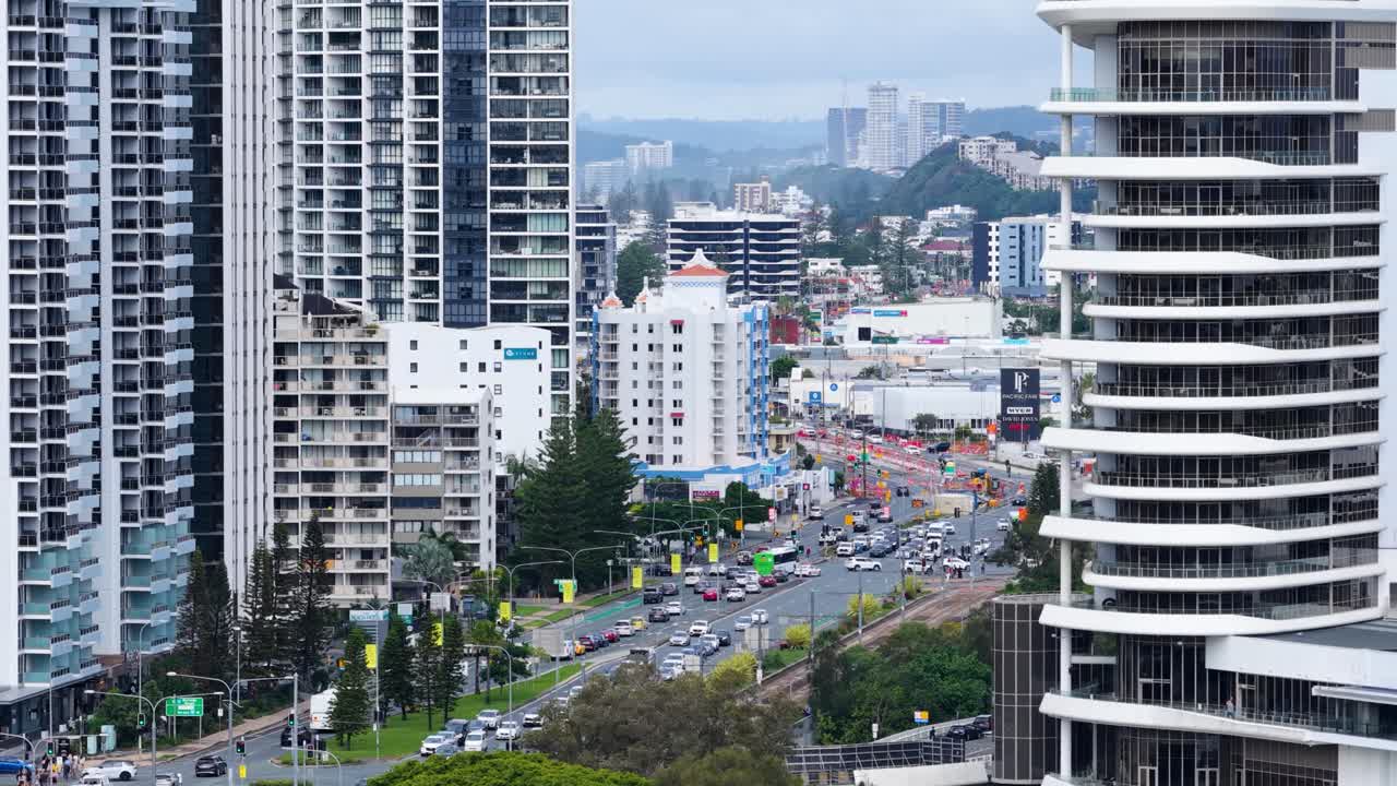 Aerial view of busy city traffic on Gold Coast Highway, surrounded by skyscrapers and urban landscape under overcast skies