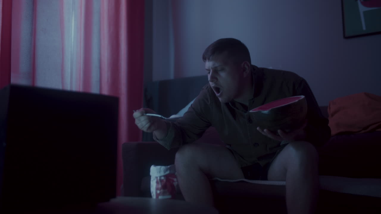 Man Eating Watermelon While Watching TV at Home