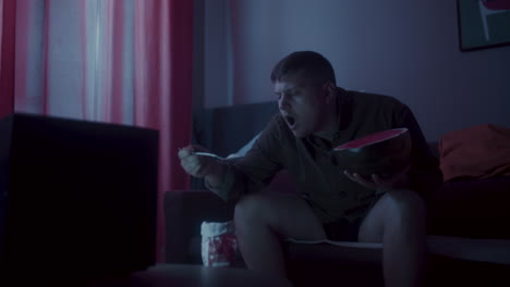 man eating watermelon while watching tv at home
