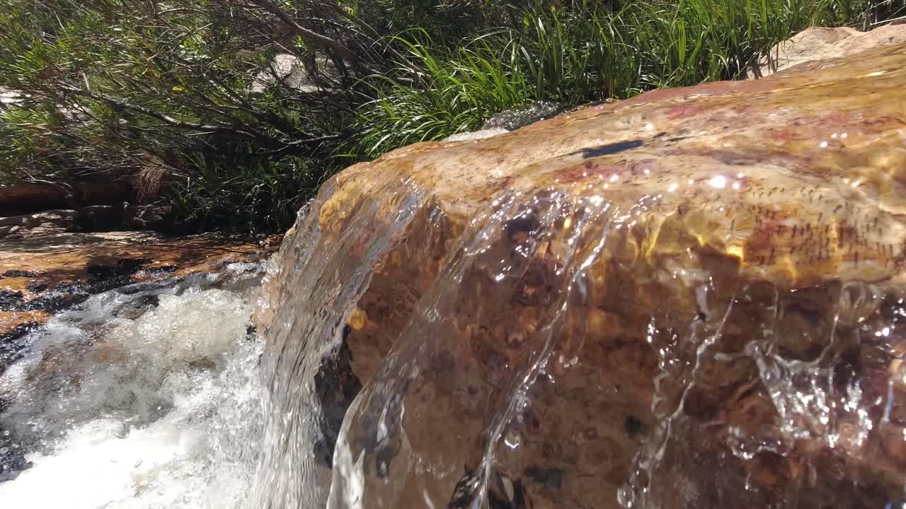 agua cristalina que fluye sobre una roca en un arroyo de montaña