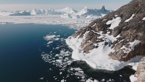 drone over sea and rocky coastline towards ilulissat icefjord