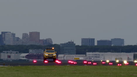 airport runway with vehicle and cityscape