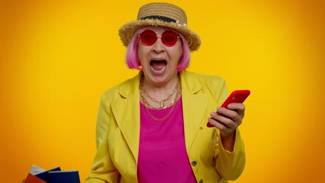 Senior-woman-grandmother-with-mobile-phone-celebrating-winning-holiday-resort-vacation-tickets-pass