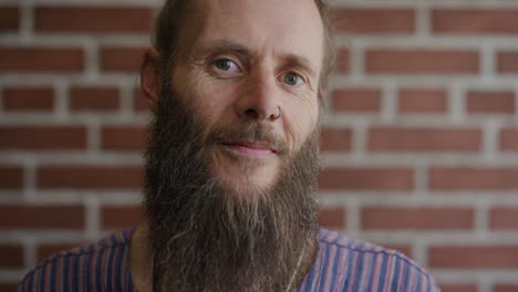 close up portrait mature bearded hippie man smiling confident enjoying relaxed carefree lifestyle eccentric caucasian male wearing nose ring on brick wall background