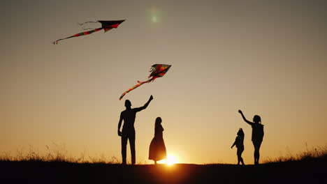 familia activa con niños lanza cometas en un lugar pintoresco al atardecer