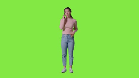 Full-Length-Studio-Shot-Of-Woman-Answering-Mobile-Phone-Against-Green-Screen