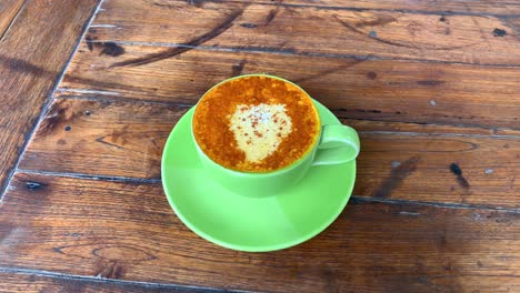 vista superior de un café con leche de cúrcuma con leche de coco y canela en polvo encima