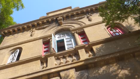 Slow-motion-shot-of-a-partly-open-window-of-Goolbai-Maternity-Home-during-a-clear-sunny-day-in-Karachi,-Pakistan