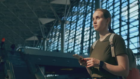 woman traveler with a backpack at the airport looking at the scoreboard-departures looking for your flight