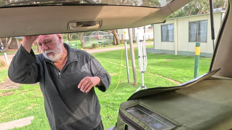a man organizes and looks at a map in the back of a vehicle at a campsite
