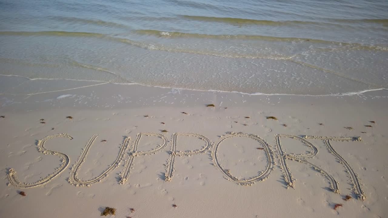 모래 위에 물이 찰싹 달라붙는 해변의 모래에 쓰여진 정적 지지 샷