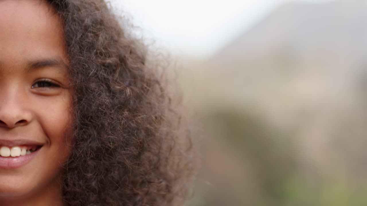 Niño de pie a la izquierda, cambiando su expresión de neutral a una leve sonrisa y parpadeando frente a una ladera, con espacio para texto.