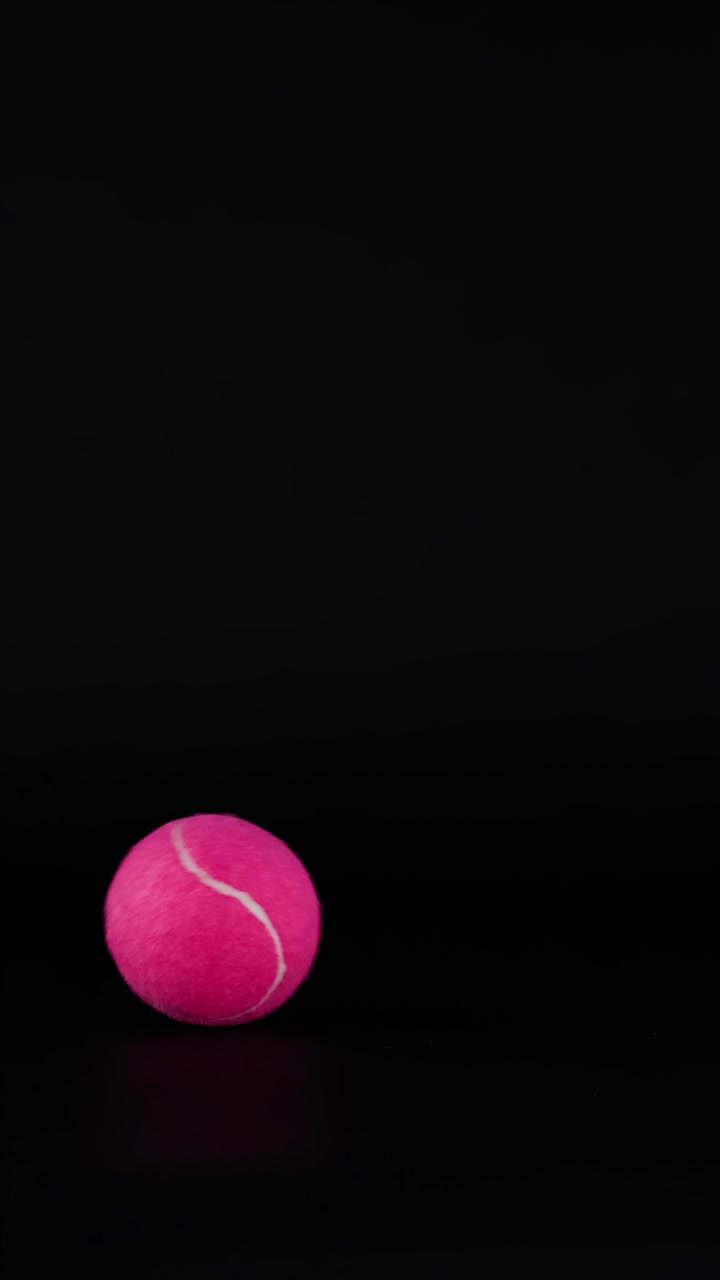 Vibrant tennis balls moving against a dark background