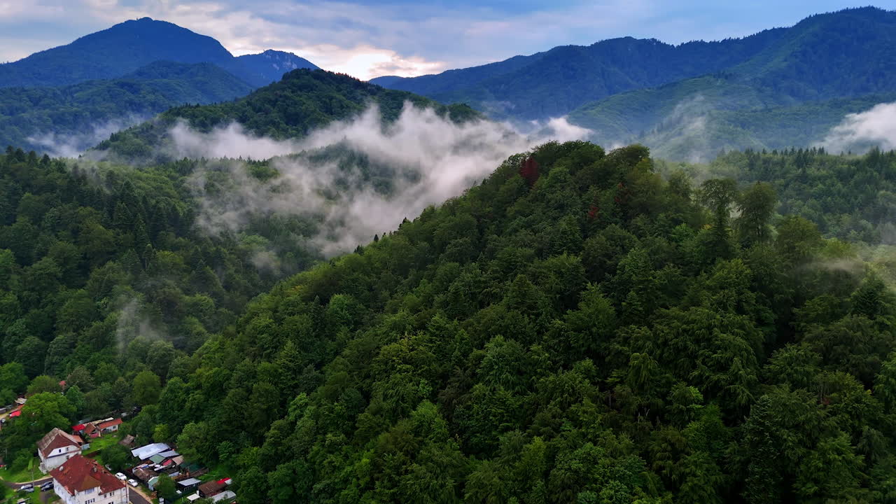 Montagne nebbiose al tramonto. Verdi colline lussureggianti si ergono sullo sfondo, avvolte nella nebbia mentre la sera si avvicina, creando un'atmosfera tranquilla.