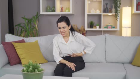 mujer con dolor de estómago en casa.