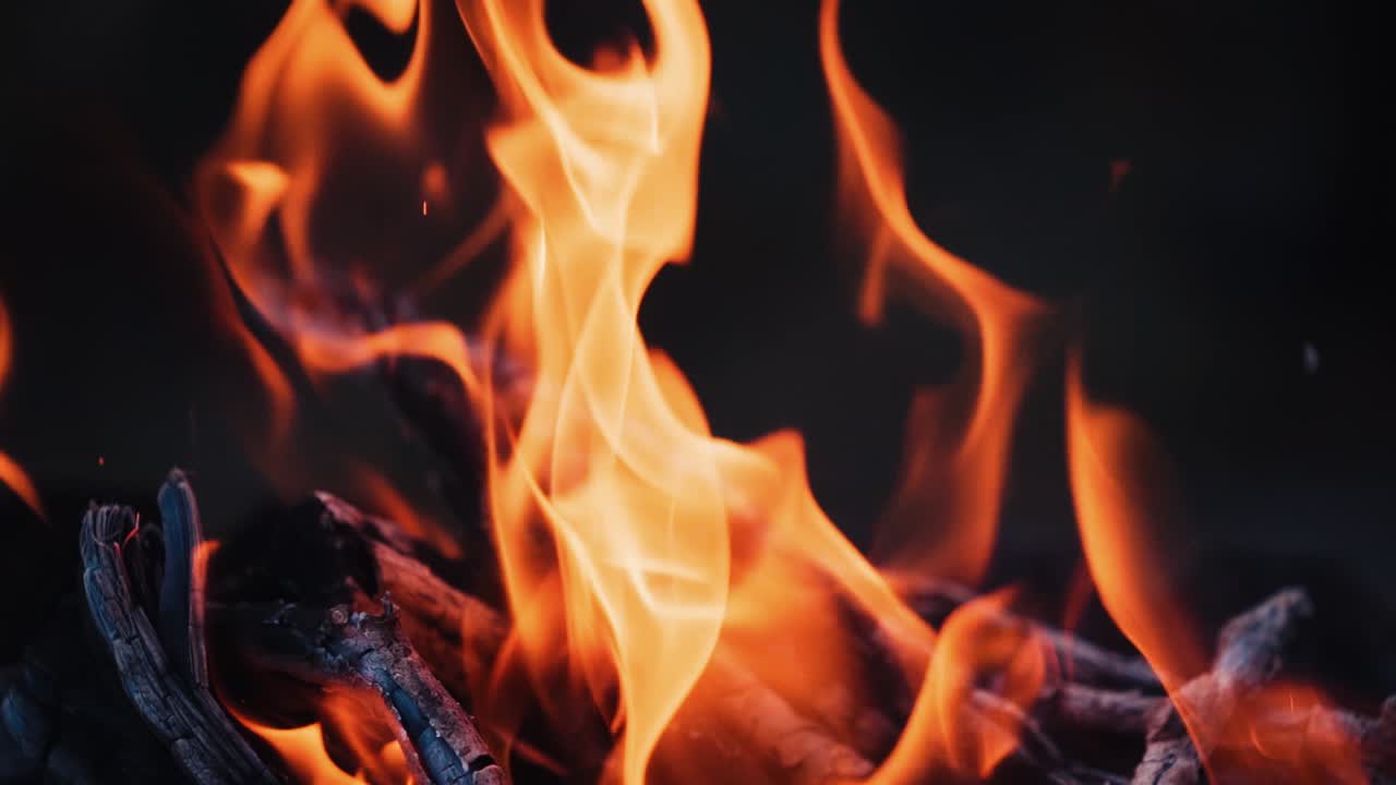 Falò che brucia di notte. Fiamme di fuoco su sfondo nero al rallentatore.