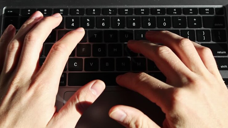 Static overhead shot of Caucasian person typing on a laptop keyboard on desk