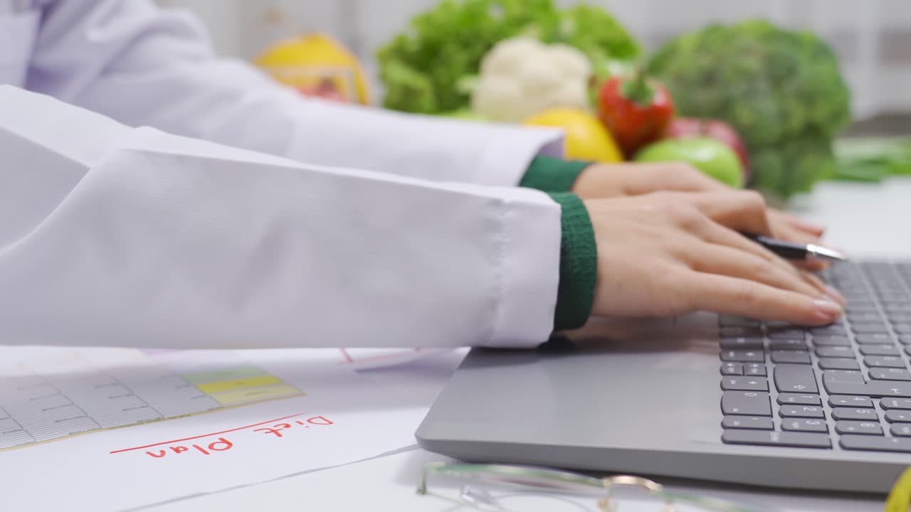 nutricionista trabajando en una mesa llena de verduras y frutas.