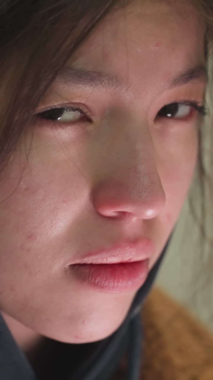 어린 소녀의 눈물을 흘리는 얼굴의 클로즈업, 약간 망진창의 머리카락과 깊은 우울한 표정, 그녀의 눈은 아래로 던져, 우려와 성찰의 상태를 반영합니다.