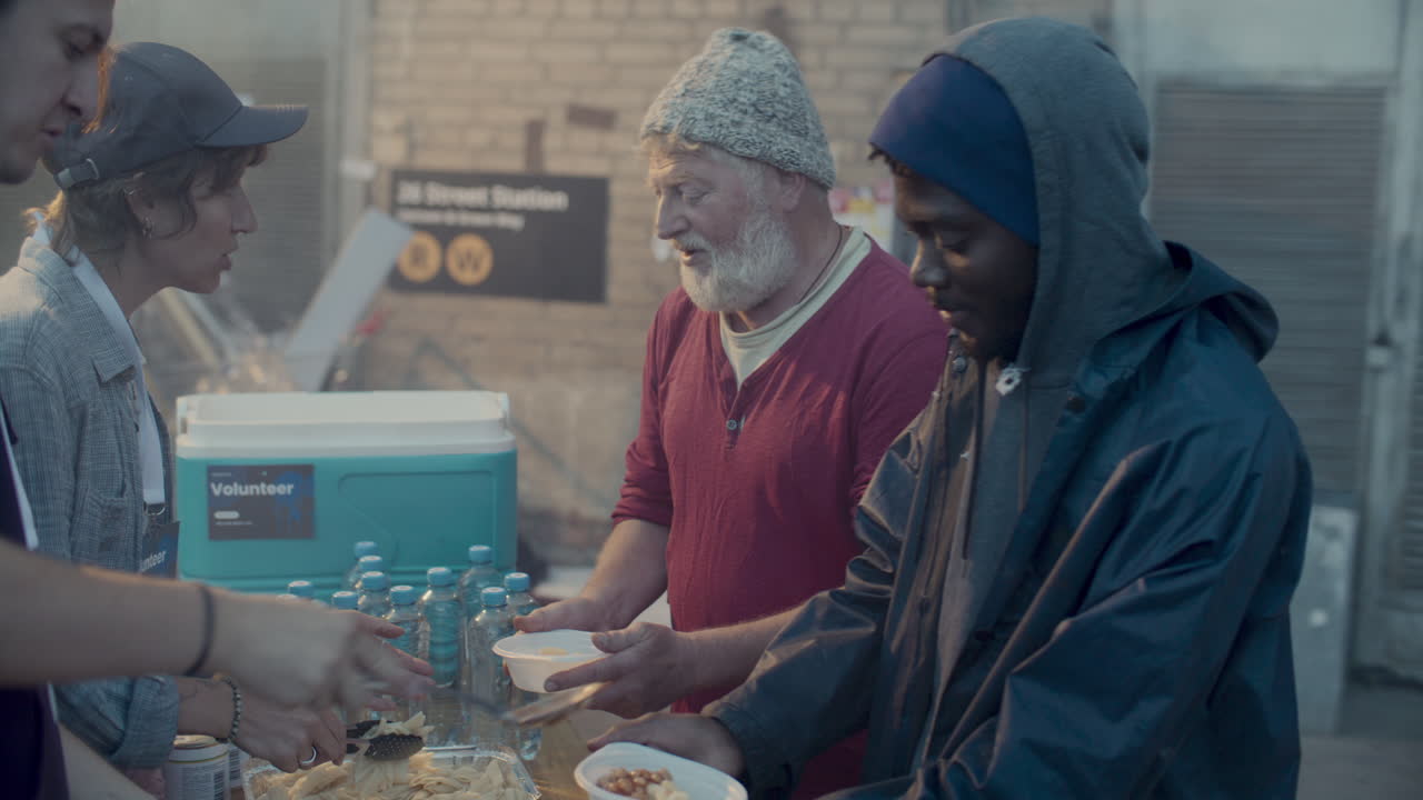 Volunteers Serving Food to Homeless People in Urban Alleyway