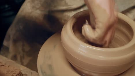 apprentice learning clay pottery on ancient kick operated revolving wheel