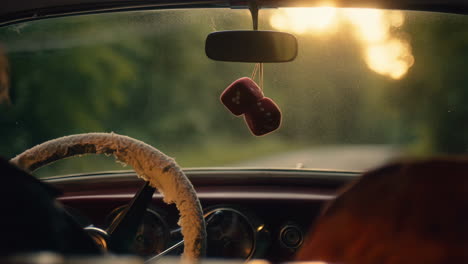 fuzzy dice in a vintage car at sunset
